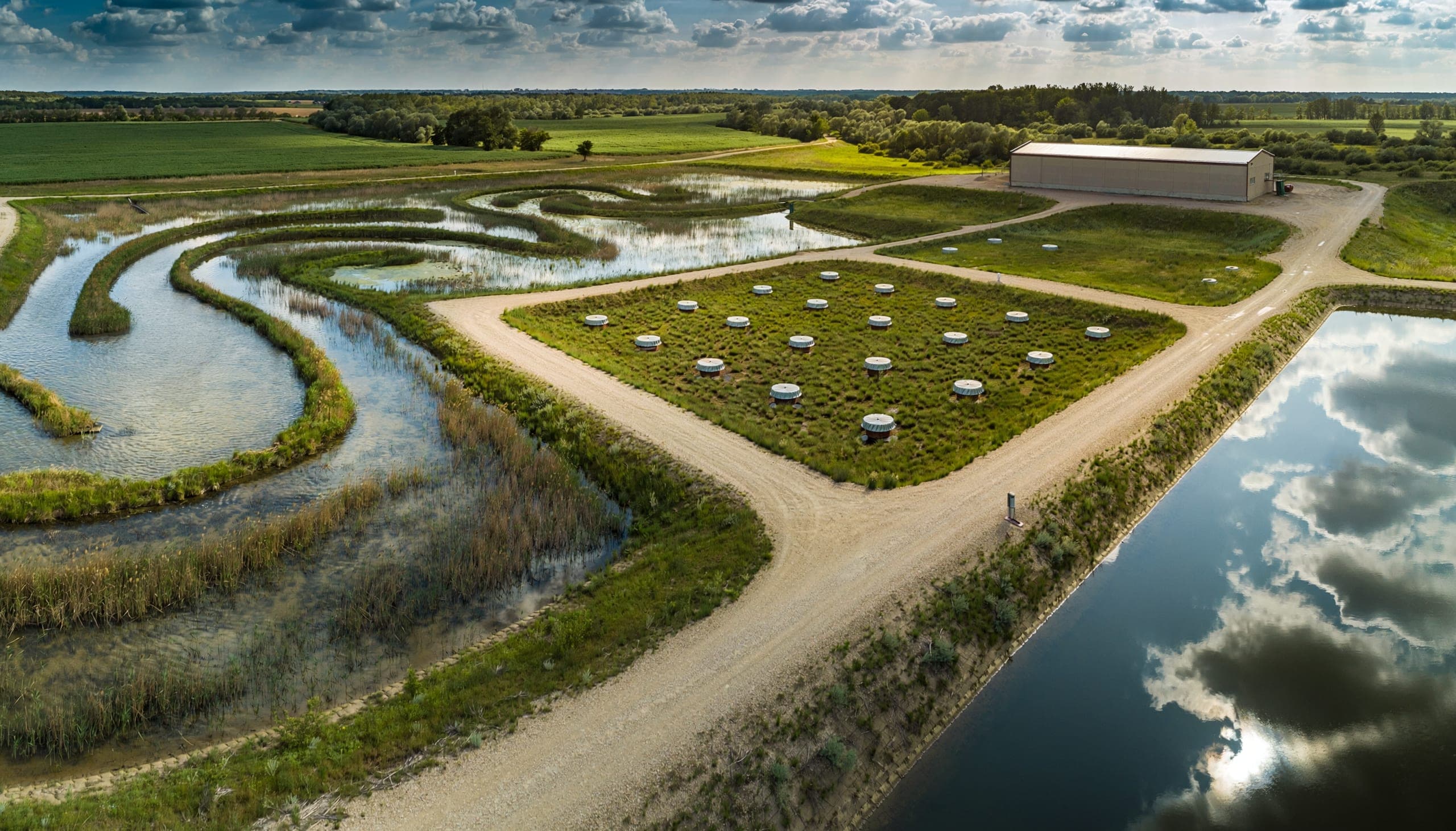 Aerial view of a managed environmental site with treatment wetland, capped groundwater monitoring wells, and clean water infrastructure.
